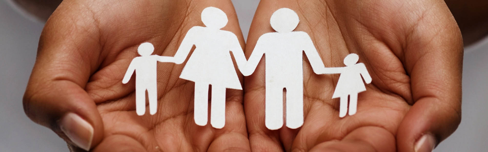 Image of hands holding a paper cut-out family
