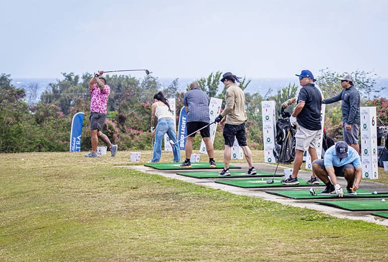 People in a lign swing golf club at golf challenge area outdoors in grass
