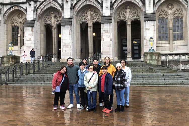 Photo of a group of students and faculty in front of an academic building