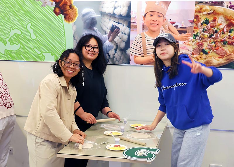 A photo of three women making pizza with mushrooms