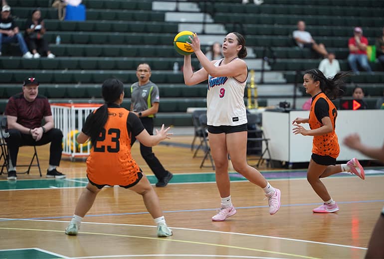 Mia San Nicolas shoots basketball with opponents flanking