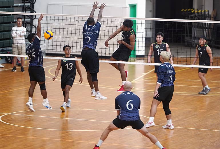 Wider shot of players attempting to block a spike